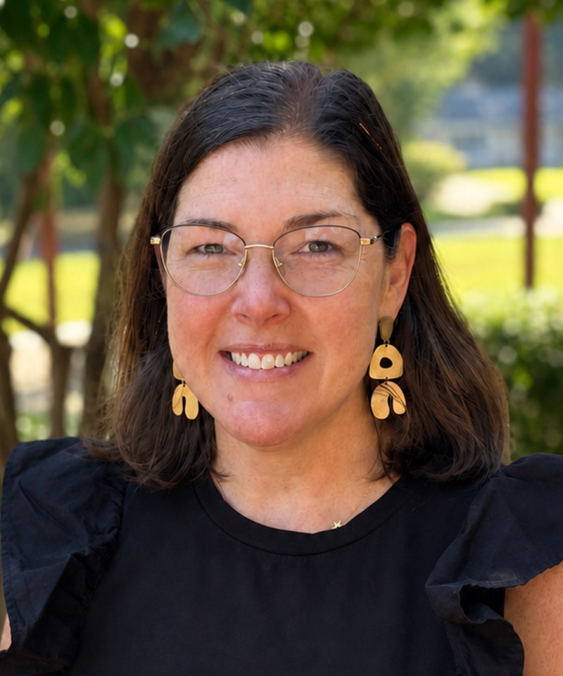 Rev. Jen Kirby Evans, smiling outdoors under a tree